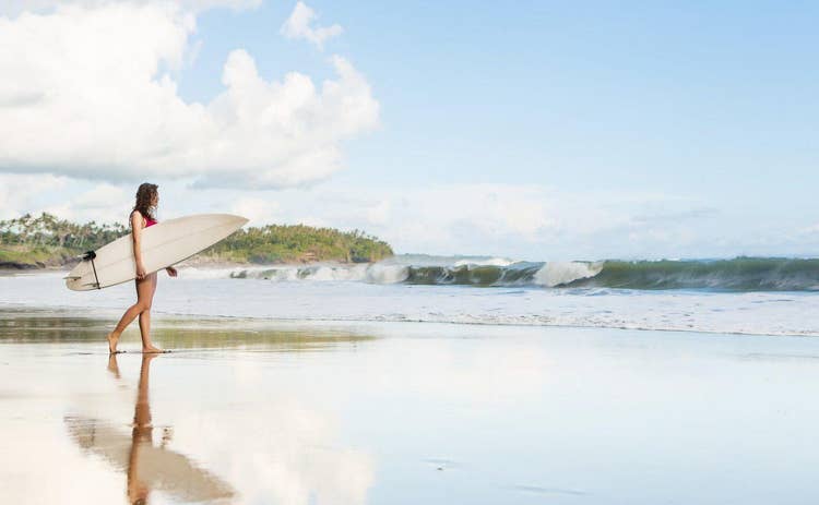 Young lady with surfboard going to the ocean at surf spot
